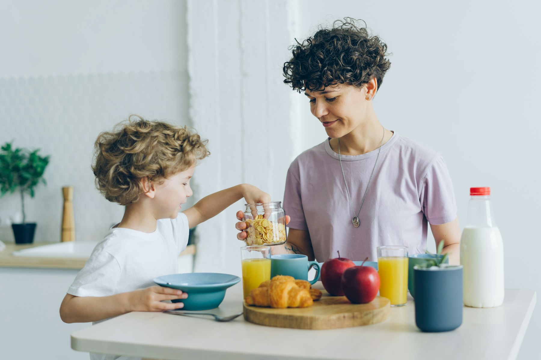 Madre y su hijo compartiendo un desayuno con frutas en casa